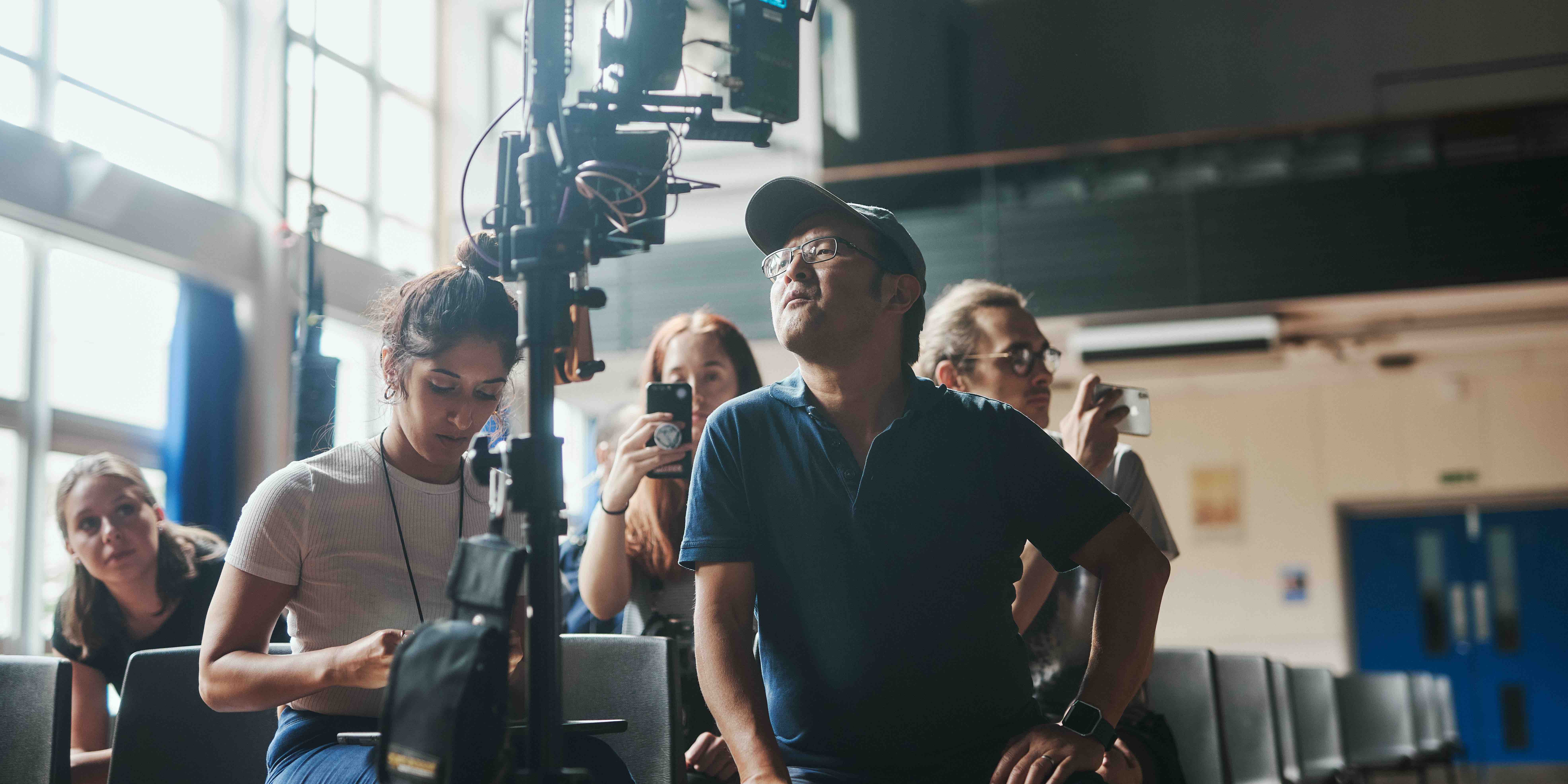 Behind the scenes on British People, the director and camera team at the monitor in a school hall
