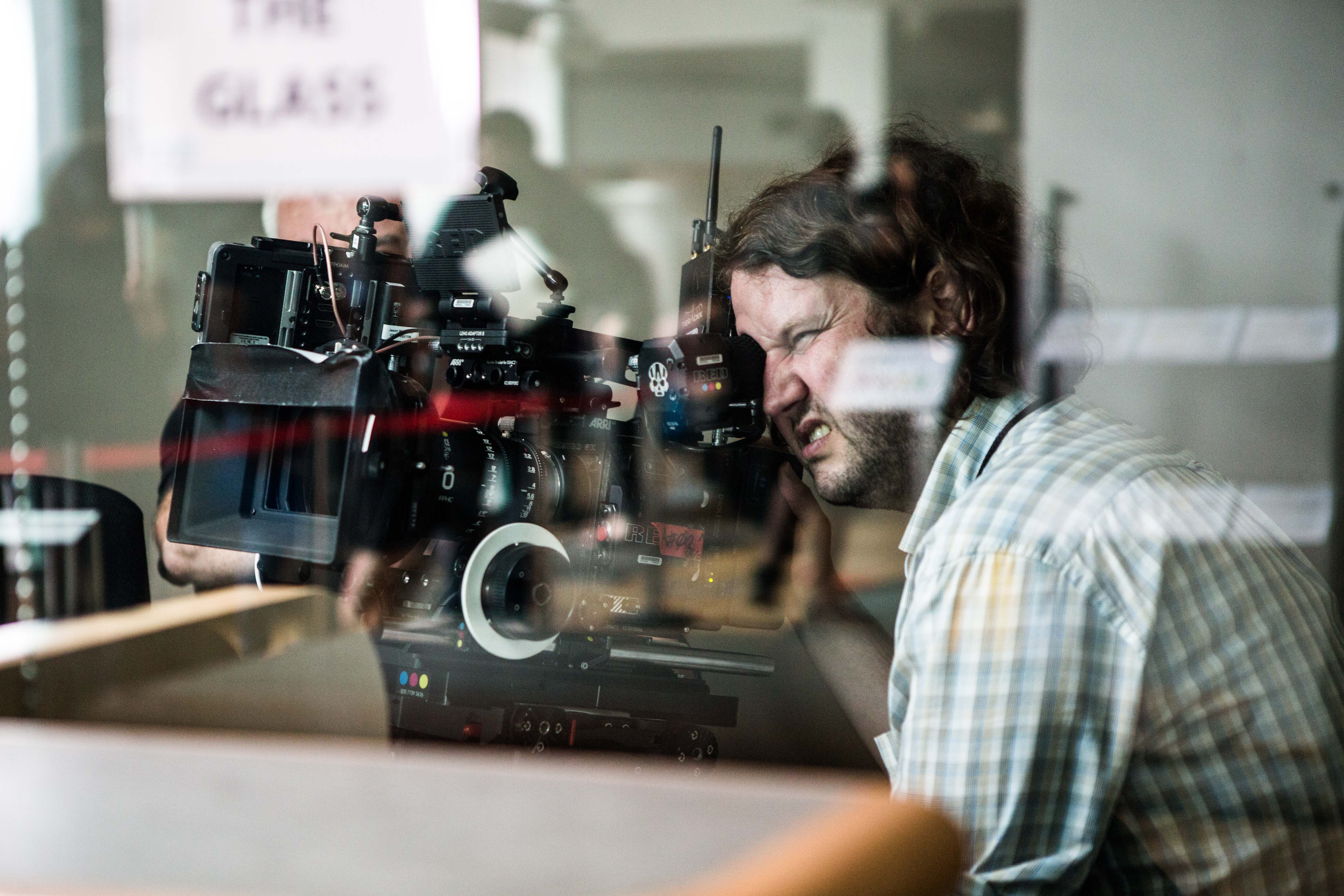 Behind the scenes on Leave to Remain, the director watching the camera through a glass partition